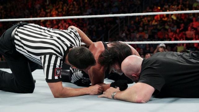 The doctor and referee on the mat checking on Sting in WWE