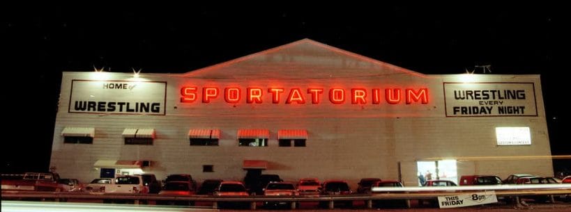 Iconic Dallas Sportatorium at night with the name lit up in red.