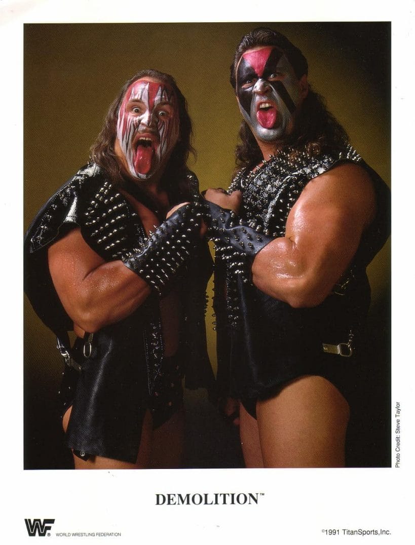 Tag Team Demolition (Crush and Smash version) in black leather studded vests, red black and silver makeup on their face and their tongues hanging out