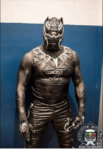 Rey Mysterio and his portrayal of the King Of Wakanda, The Black Panther. Rey donned the suit back in November 2017 in a four-way match against La Mascara, Rush and Penta Zero M.  The suit included T’chilla’s silver iconic necklace and the masked wings curled up into feline ears.