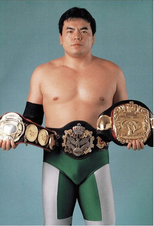 Mitsuharu Misawa in his patented emerald green tights holding all the belts that comprised the Triple Crown Heavyweight Championship: AJWP’s most prestigious title.